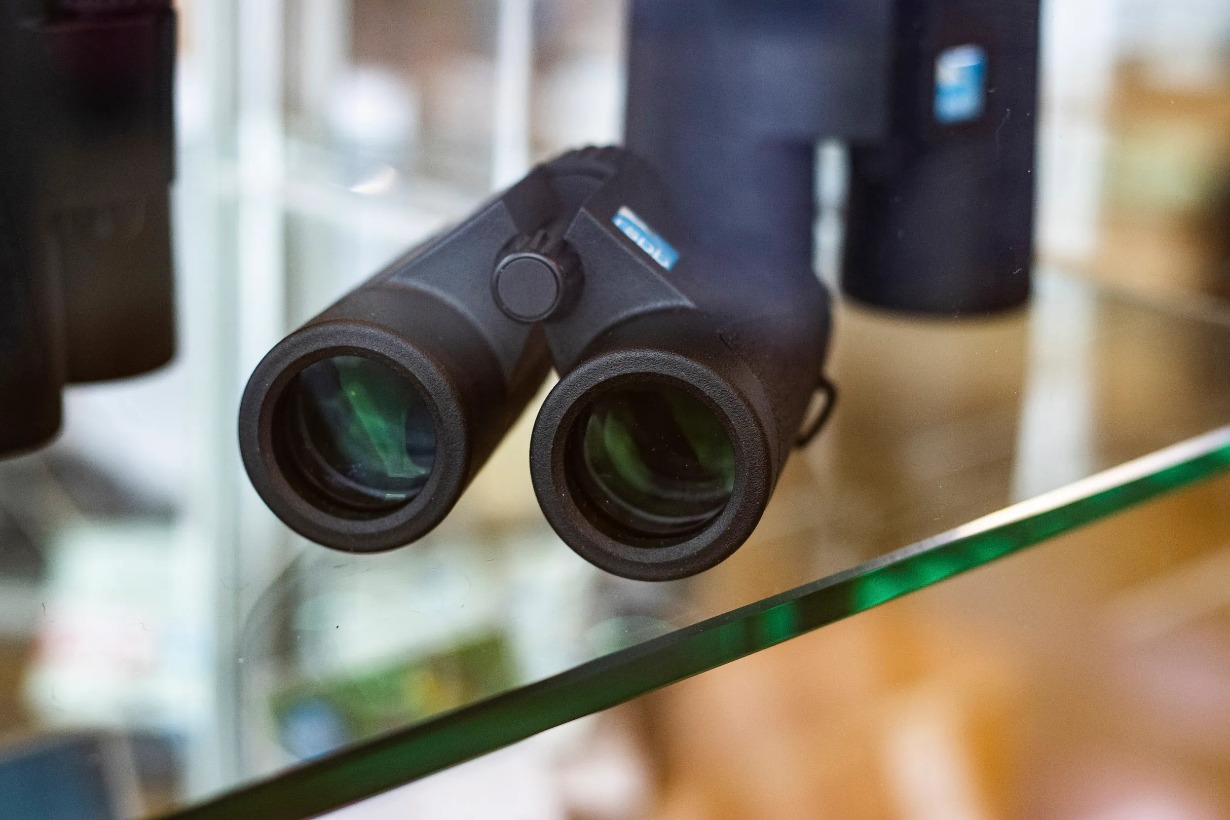 A set of Binoculars sat on a glass display in a shop.