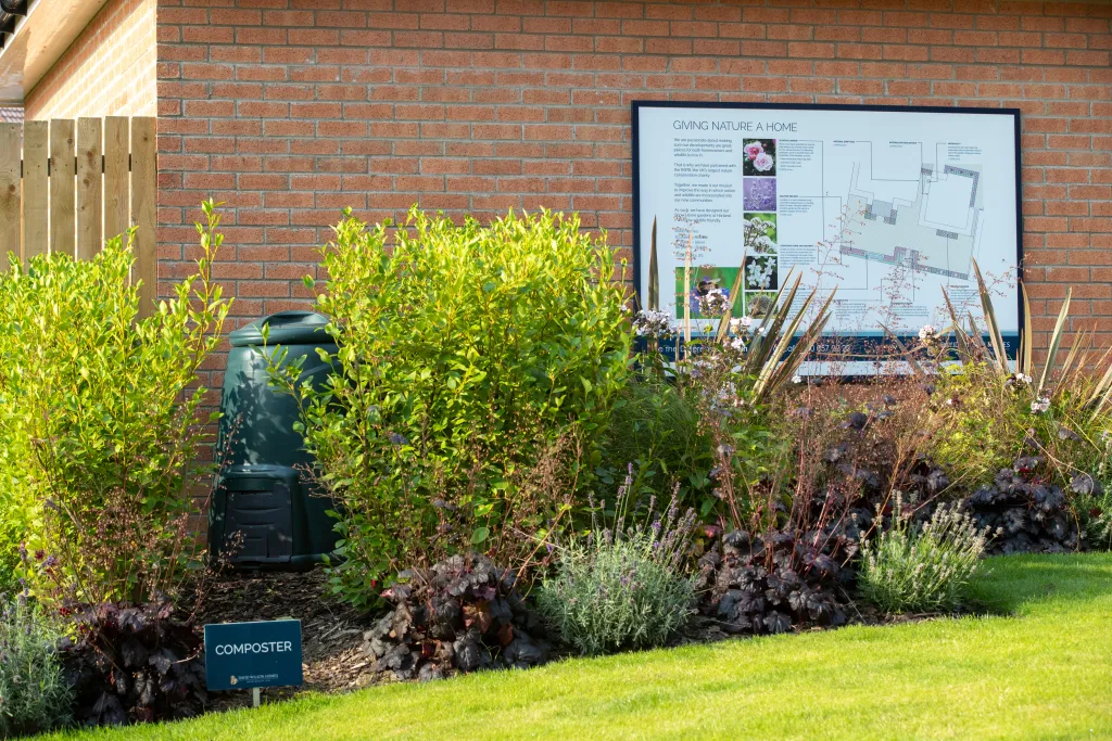 Composter with the site map on the wall amongst plants.