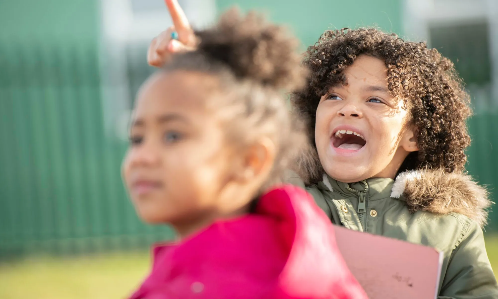 Children in winter clothes looking up at the sky, taking part in big schools birdwatch
