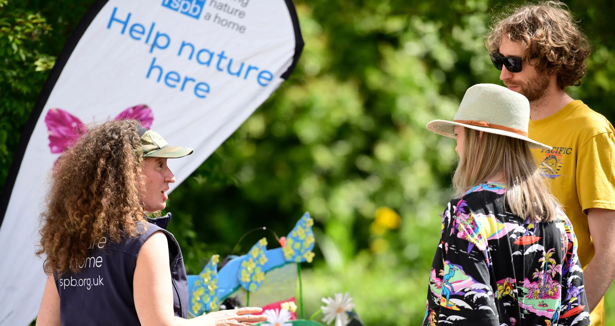 A member fundraising in front of a stall talking to two members of the public.