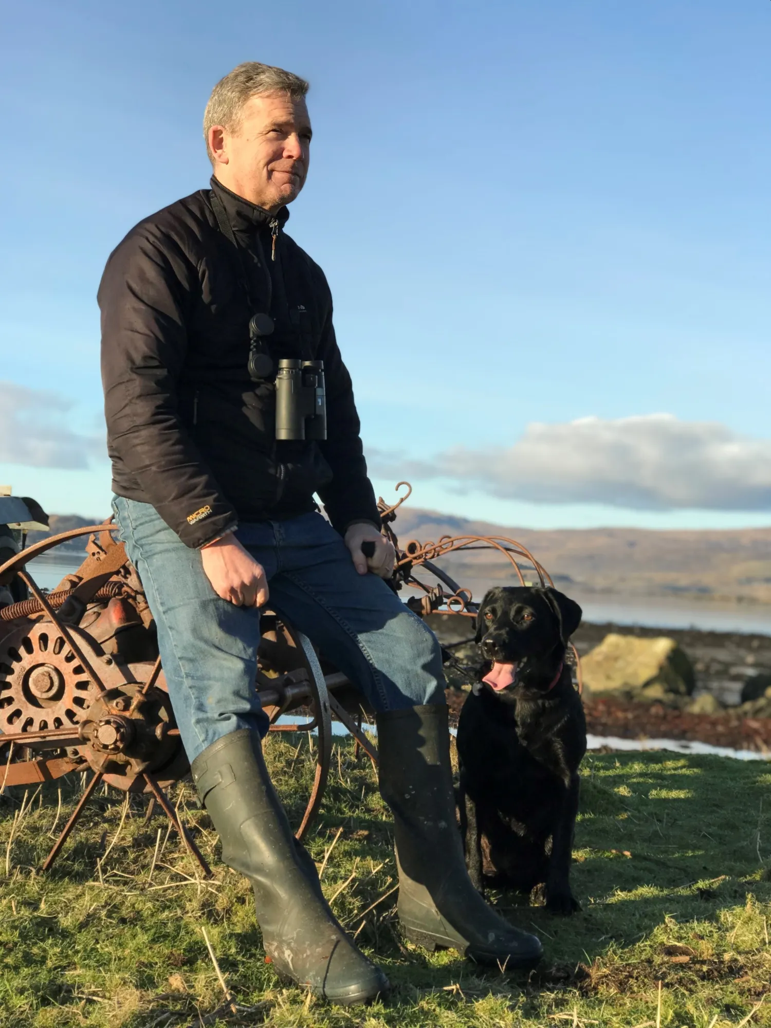 Dave Sexton and dog sat against old machinery 