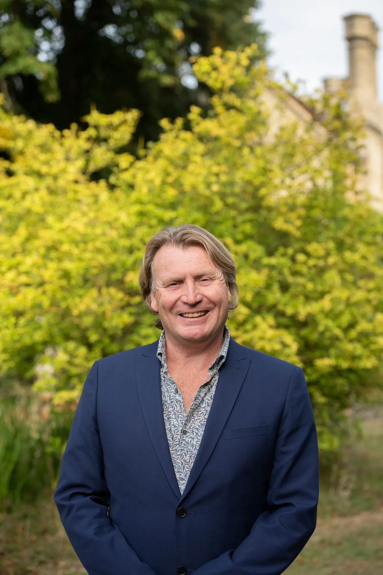 David Domoney smiling against a background of green shrubbery